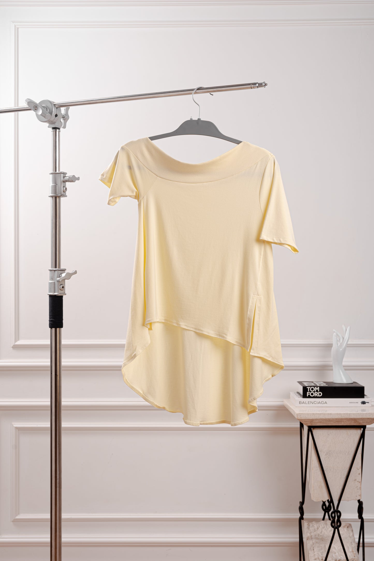 Polo Asimétrico con Cola Larga, color amarillo mantequilla, siguiendo el trend butter yellow con diseño fluido y deconstruido YouSoul. Detalle del Rib profundo que luce el hombro del Polo Asimétrico con Cola, inspirado en la silueta Rectangular. Vista trasera del polo asimétrico mostrando la caída dramática de la cola larga.