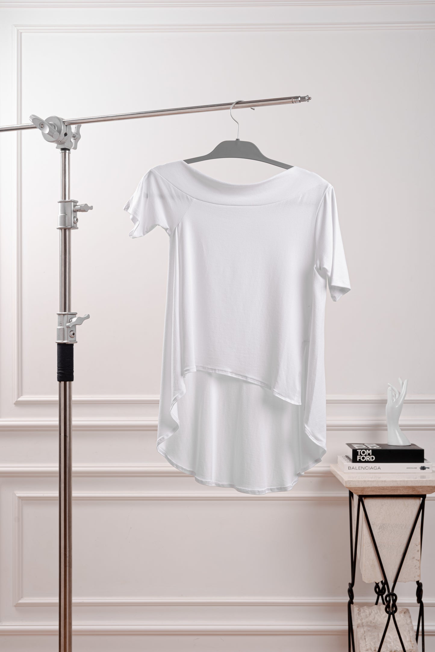 Polo Asimétrico con Cola Larga, color blanco, diseño fluido y deconstruido YouSoul. Detalle del Rib profundo que luce el hombro del Polo Asimétrico con Cola, inspirado en la silueta Rectangular. Vista trasera del polo asimétrico mostrando la caída dramática de la cola larga.