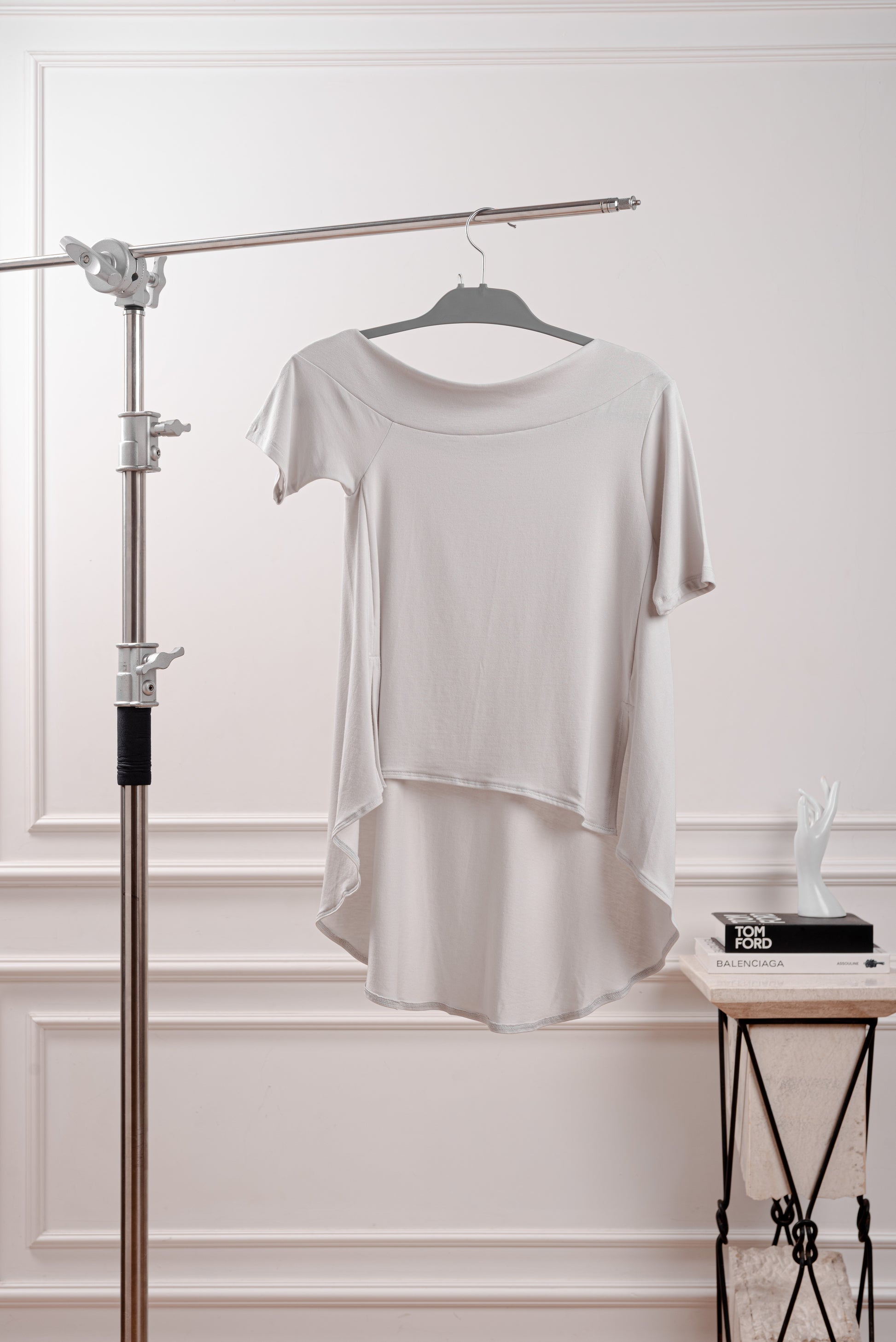 Polo Asimétrico con Cola Larga, color gris, con diseño fluido y deconstruido YouSoul. Detalle del Rib profundo que luce el hombro del Polo Asimétrico con Cola, inspirado en la silueta Rectangular. Vista trasera del polo asimétrico mostrando la caída dramática de la cola larga.