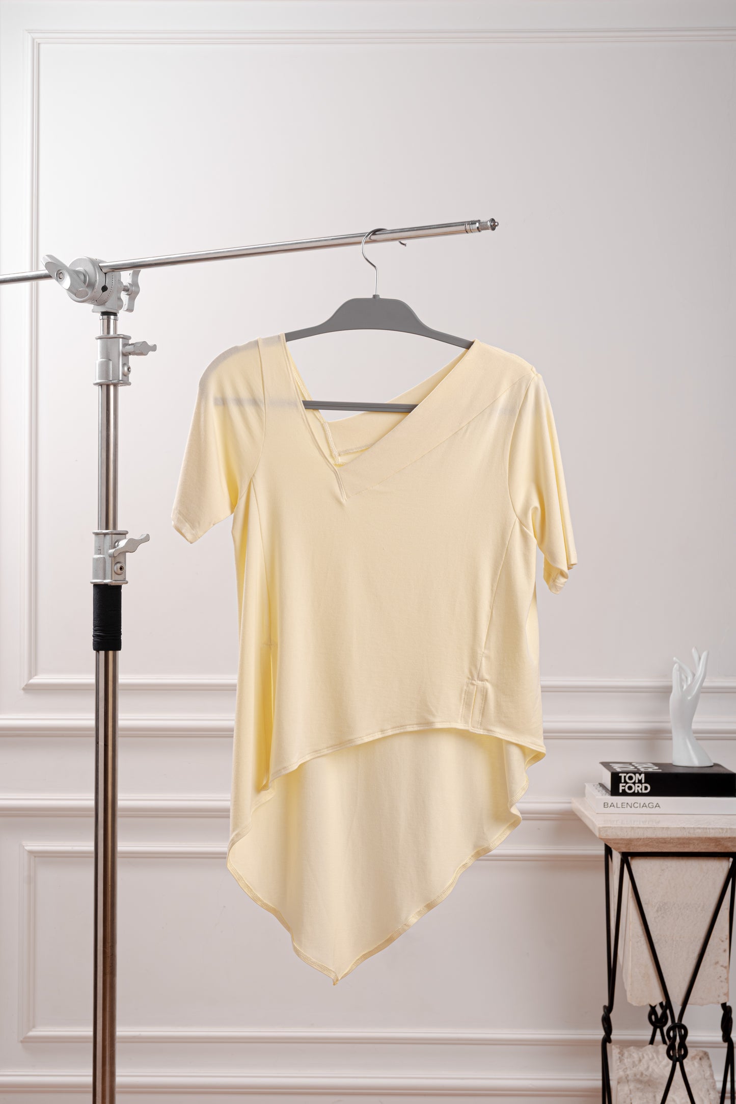 Vista de la cola en punta y fluida del polo asimétrico amarillo mantequilla siguiendo la tendencia butter yellow, diseñado para el dinamismo de la silueta Triángulo Invertido. Primer plano del sofisticado cuello en V irregular del polo de Algodón Pima Modal.