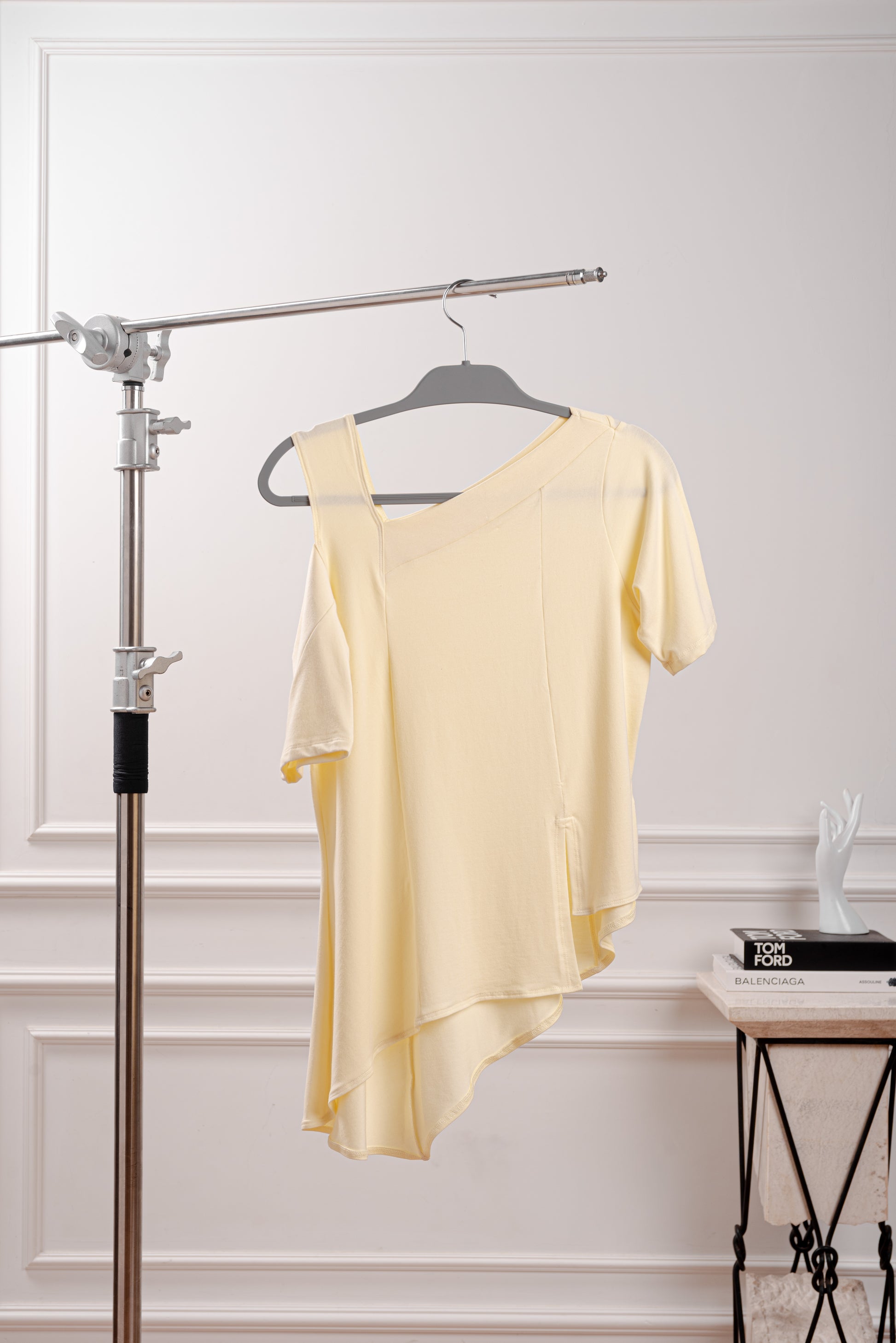 Polo Asimétrico con Hombro Descubierto, color amarillo mantequilla, siguiendo el trend butter yellow, con elegante contraste para un look minimalista. Detalle del Rib que atraviesa el hombro y la franja sin costura del polo asimétrico. Primer plano de la textura suave y transpirable del tejido Pima Modal, diseñado para la silueta Ovalada.