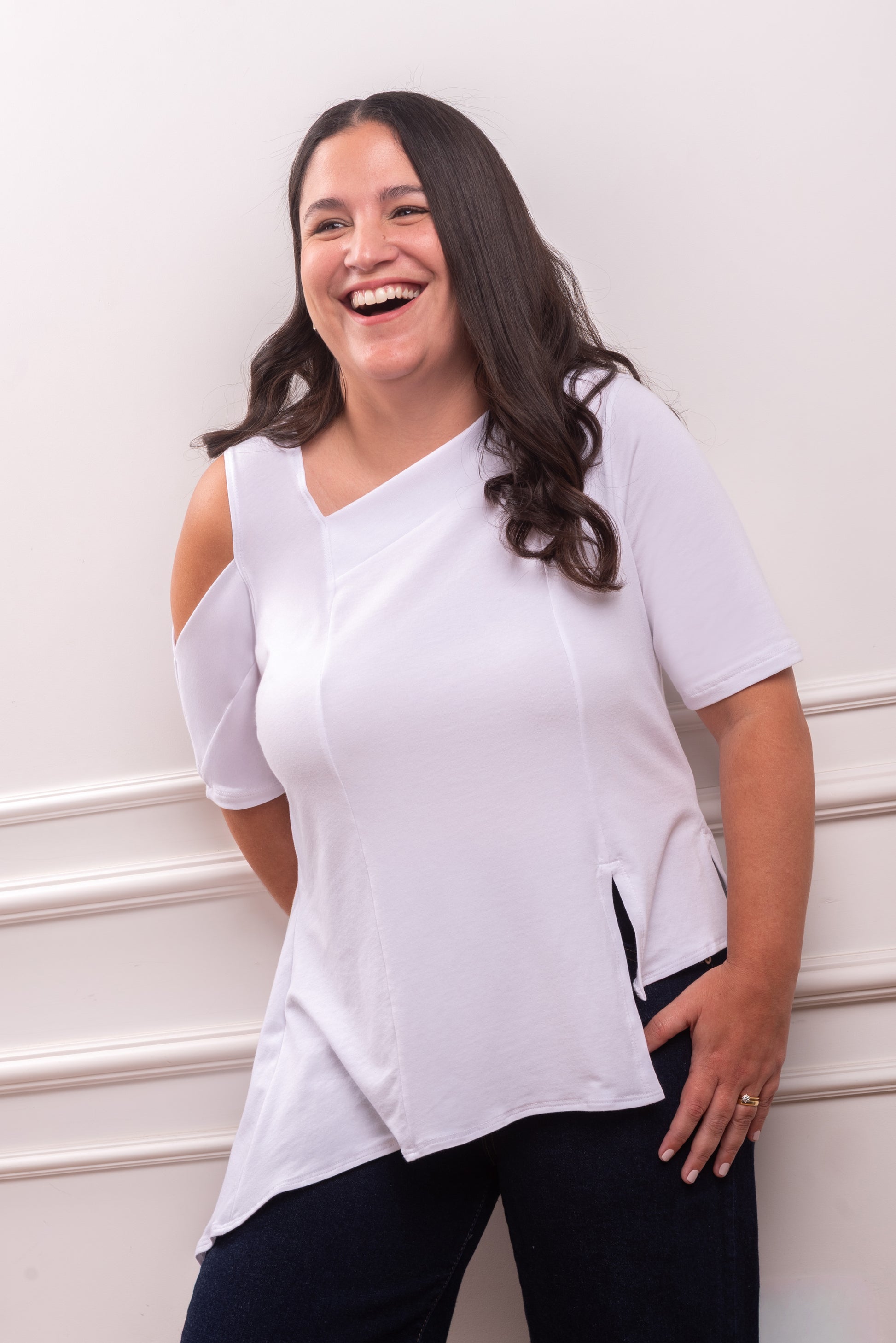 Polo Asimétrico con Hombro Descubierto, color blanco, elegante contraste para un look minimalista. Detalle del Rib que atraviesa el hombro y la franja sin costura del polo asimétrico. Primer plano de la textura suave y transpirable del tejido Pima Modal, diseñado para la silueta Ovalada.