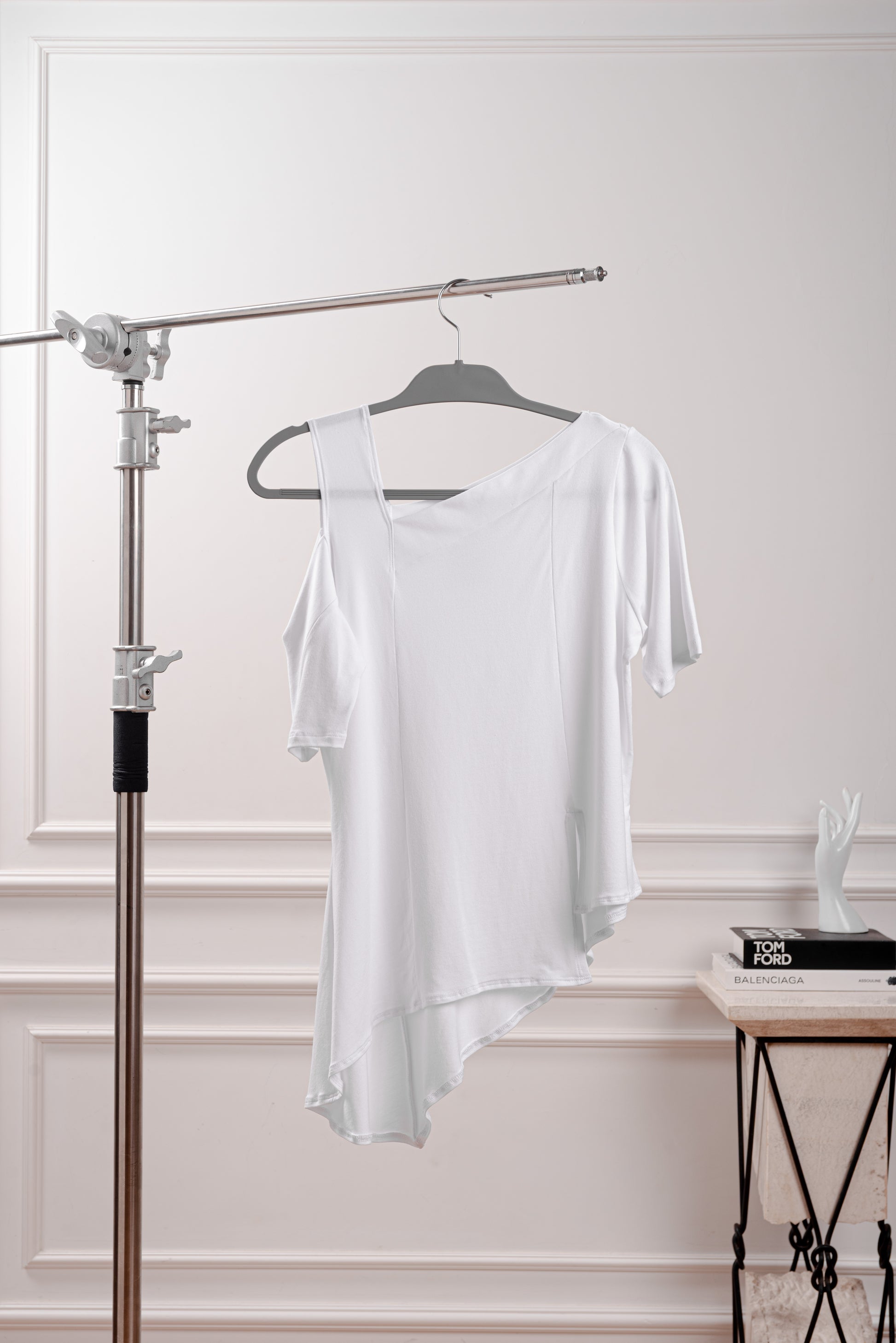 Polo Asimétrico con Hombro Descubierto, color blanco, elegante contraste para un look minimalista. Detalle del Rib que atraviesa el hombro y la franja sin costura del polo asimétrico. Primer plano de la textura suave y transpirable del tejido Pima Modal, diseñado para la silueta Ovalada.