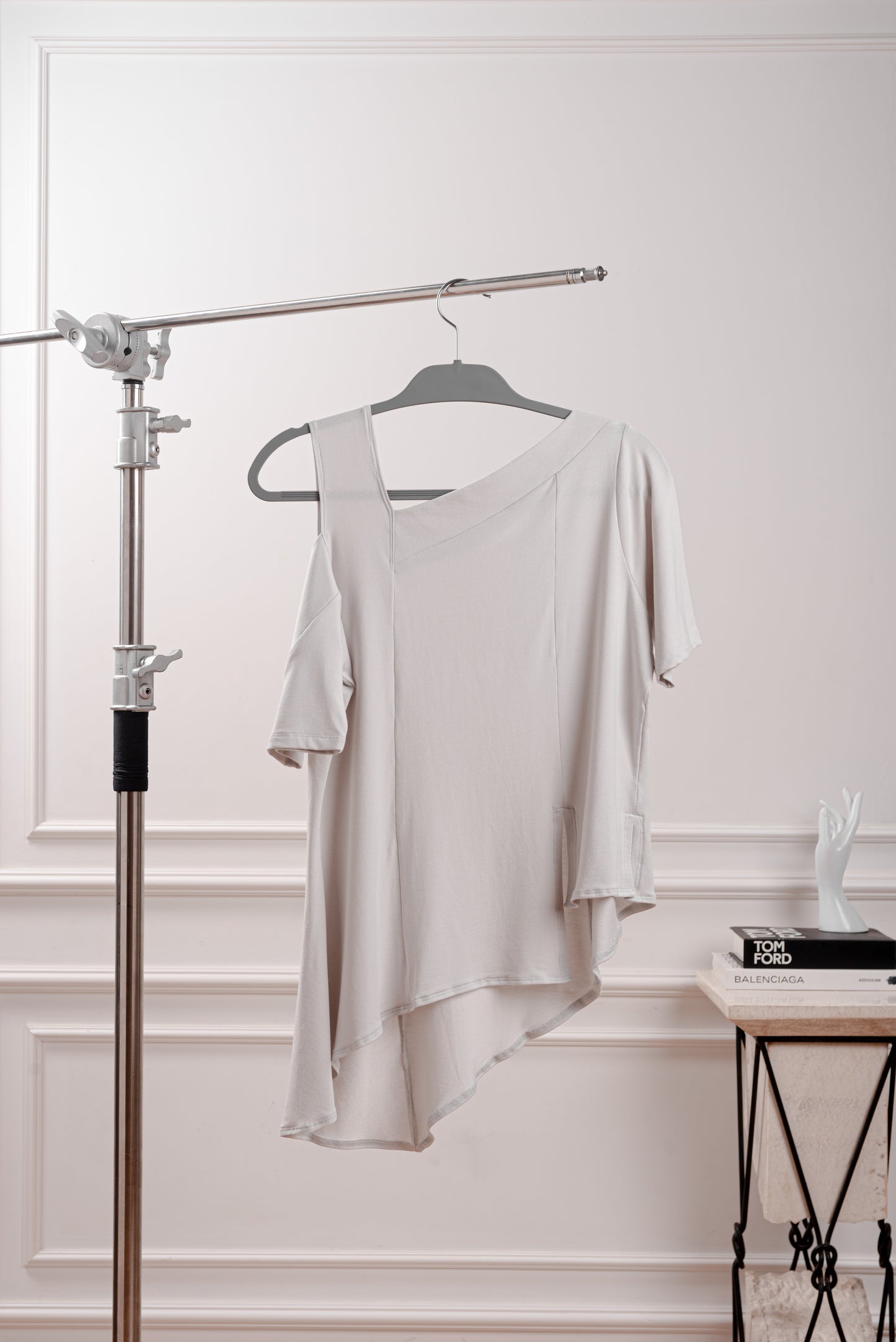 Polo Asimétrico con Hombro Descubierto, color gris, elegante contraste para un look minimalista. Detalle del Rib que atraviesa el hombro y la franja sin costura del polo asimétrico. Primer plano de la textura suave y transpirable del tejido Pima Modal, diseñado para la silueta Ovalada.