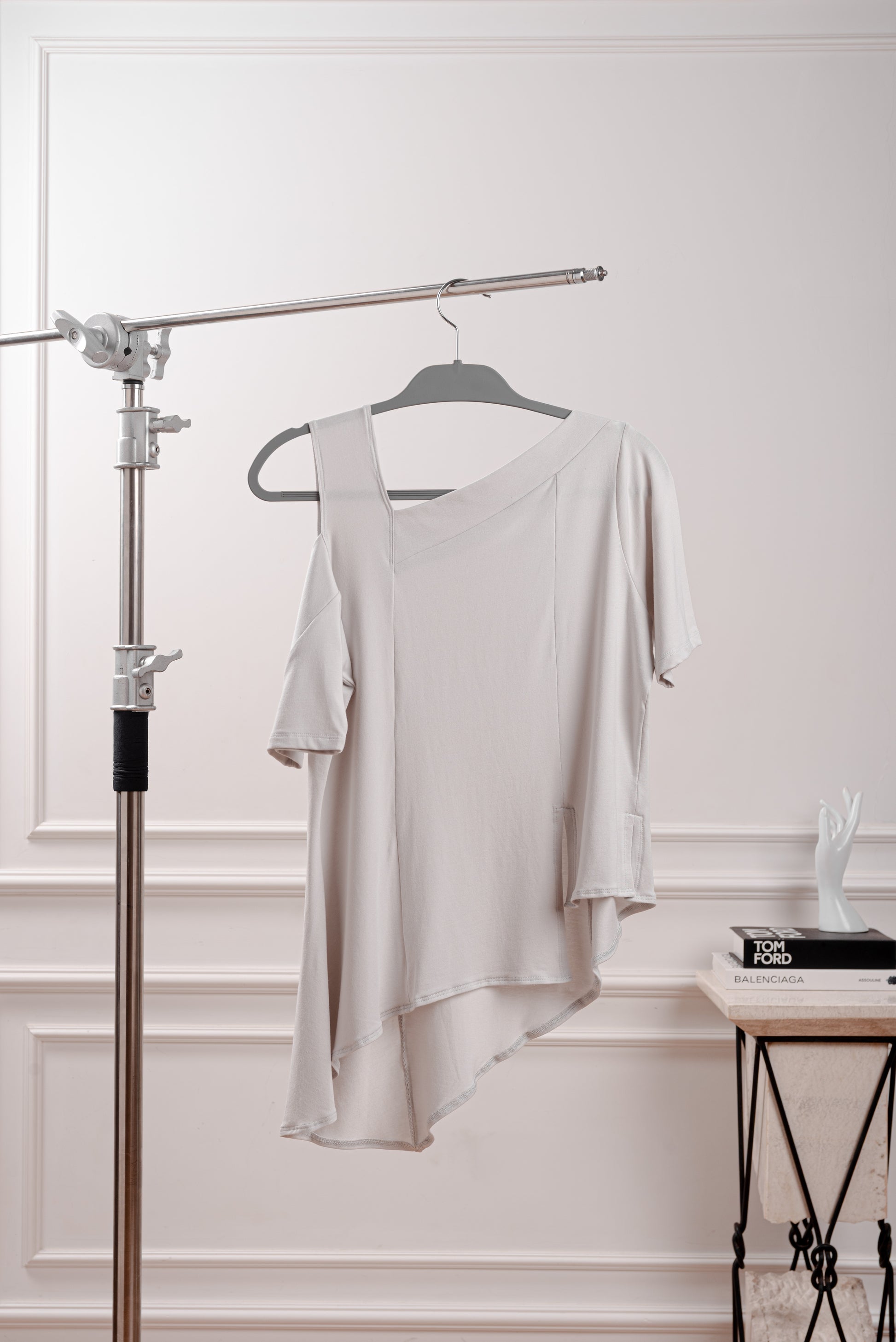 Polo Asimétrico con Hombro Descubierto, color gris, elegante contraste para un look minimalista. Detalle del Rib que atraviesa el hombro y la franja sin costura del polo asimétrico. Primer plano de la textura suave y transpirable del tejido Pima Modal, diseñado para la silueta Ovalada.